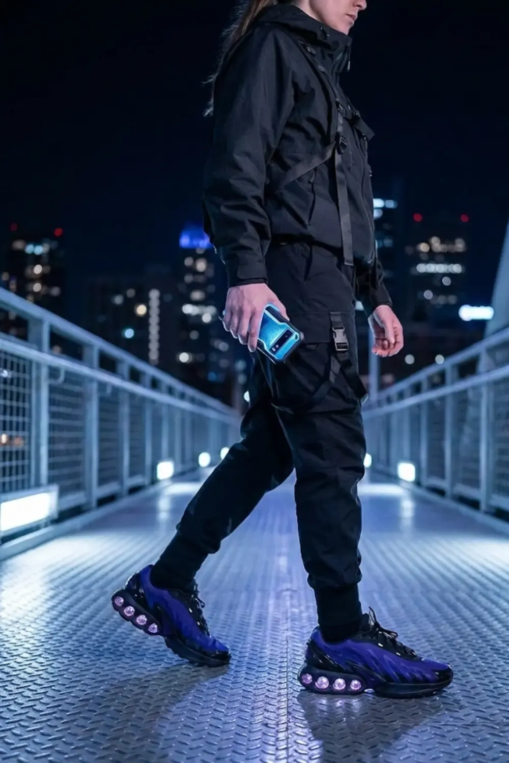 A woman in 'Techwear' gear, looking like she belongs in a futuristic city with Nike Air Max DN