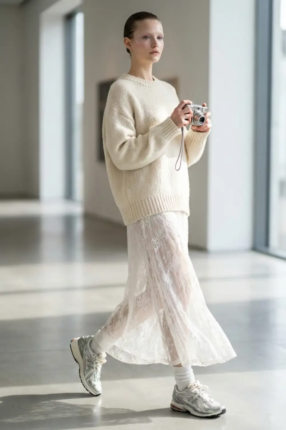 A female model embodying the 'Wrong Shoe Theory' aesthetic, wearing a high-contrast romantic-tech outfit. With New Balance 1906r